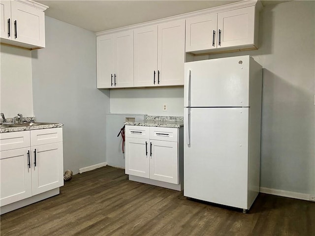 kitchen with dark wood-type flooring, white cabinetry, freestanding refrigerator, and baseboards