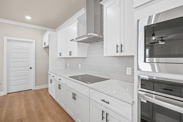 kitchen with light wood-style flooring, tasteful backsplash, stainless steel appliances, white cabinets, and wall chimney range hood