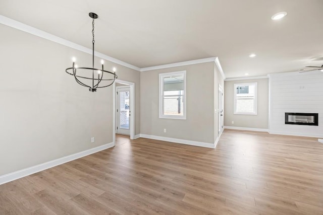 unfurnished living room with baseboards, a large fireplace, ornamental molding, and light wood finished floors