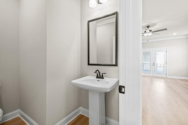 half bathroom featuring a sink, toilet, baseboards, and wood finished floors