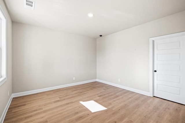 unfurnished room featuring light wood finished floors, visible vents, and baseboards