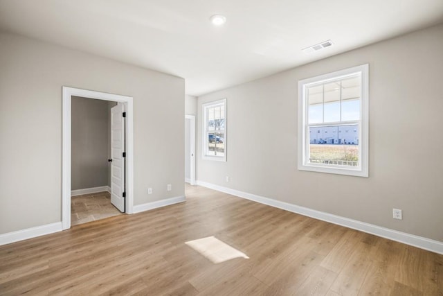 empty room featuring visible vents, light wood-style floors, and baseboards