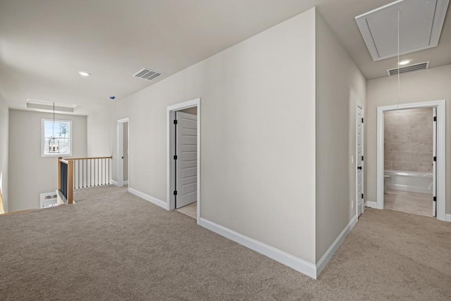 corridor featuring visible vents, carpet floors, attic access, and an upstairs landing