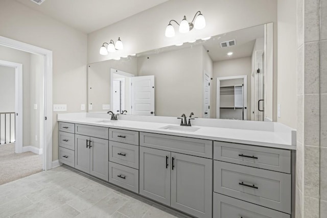 full bathroom with a walk in closet, double vanity, visible vents, and a sink