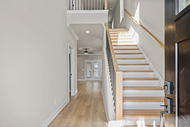 staircase featuring baseboards, wood finished floors, and a ceiling fan