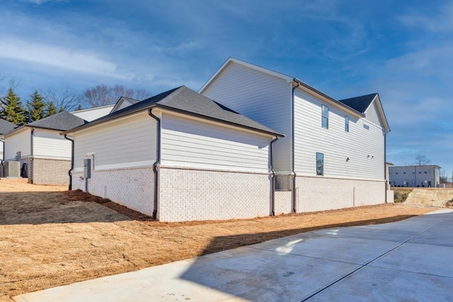 view of property exterior featuring fence, a patio area, and brick siding