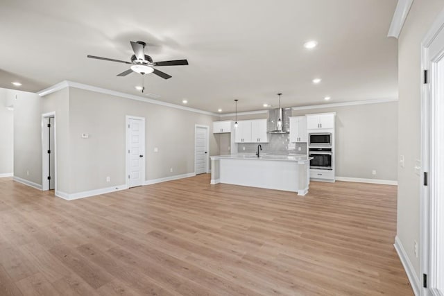 unfurnished living room with light wood finished floors, baseboards, crown molding, and a ceiling fan