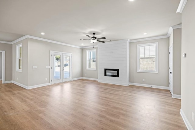 unfurnished living room with light wood finished floors, plenty of natural light, a large fireplace, and baseboards