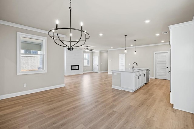 kitchen featuring open floor plan, ornamental molding, a fireplace, white cabinetry, and a sink