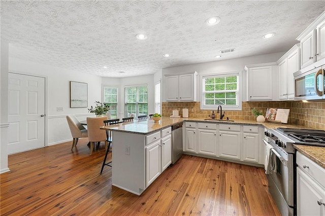 8770 Amberfield Dr, Gainesville, GA 30506 - kitchen featuring appliances with stainless steel finishes, a sink, a peninsula, hardwood / wood-style floors, and recessed lighting