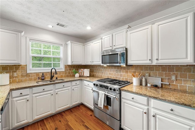 8770 Amberfield Dr, Gainesville, GA 30506 - kitchen with stainless steel appliances, a sink, white cabinets, light wood-type flooring, and recessed lighting