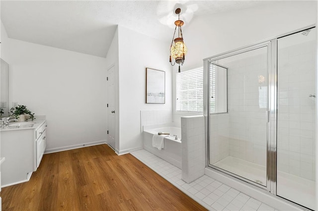 8770 Amberfield Dr, Gainesville, GA 30506 - full bathroom with vanity, a bath, a shower stall, wood finished floors, and vaulted ceiling
