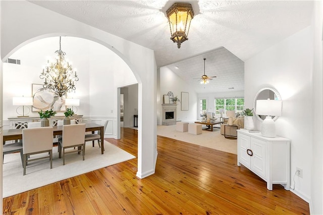 8770 Amberfield Dr, Gainesville, GA 30506 - dining area with arched walkways, light wood-type flooring, ceiling fan, lofted ceiling, and a chandelier