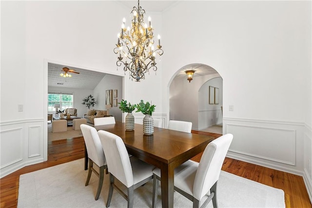 8770 Amberfield Dr, Gainesville, GA 30506 - dining space with light wood-style flooring, arched walkways, a chandelier, a wainscoted wall, and a decorative wall