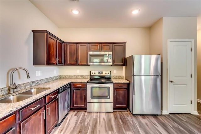 kitchen featuring light hardwood / wood-style flooring, appliances with stainless steel finishes, sink, and light stone counters