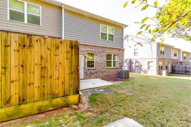 back of property with central air condition unit, a patio area, and a yard