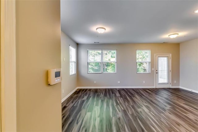 empty room featuring a wealth of natural light and dark hardwood / wood-style flooring