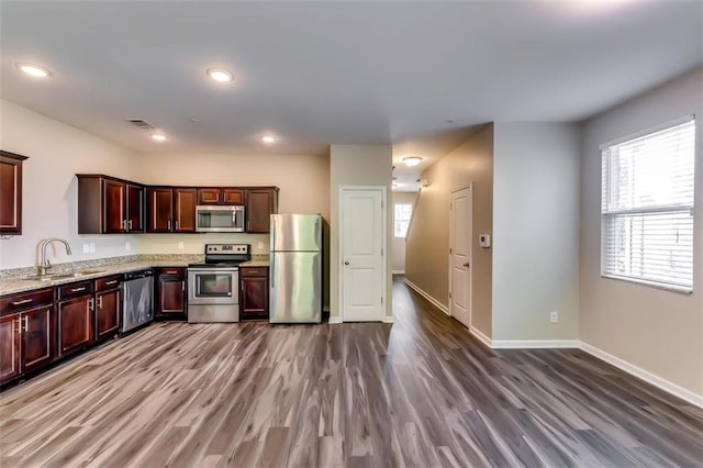 kitchen featuring light stone counters, appliances with stainless steel finishes, sink, and dark hardwood / wood-style floors