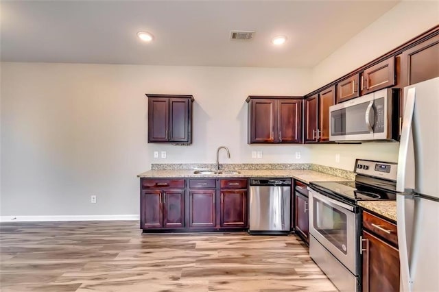 kitchen featuring light hardwood / wood-style floors, stainless steel appliances, sink, and light stone counters