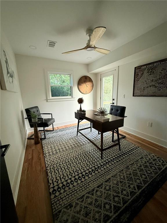 office featuring a ceiling fan, wood finished floors, visible vents, and baseboards