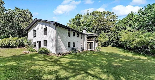 view of home's exterior with a chimney, central AC, and a yard