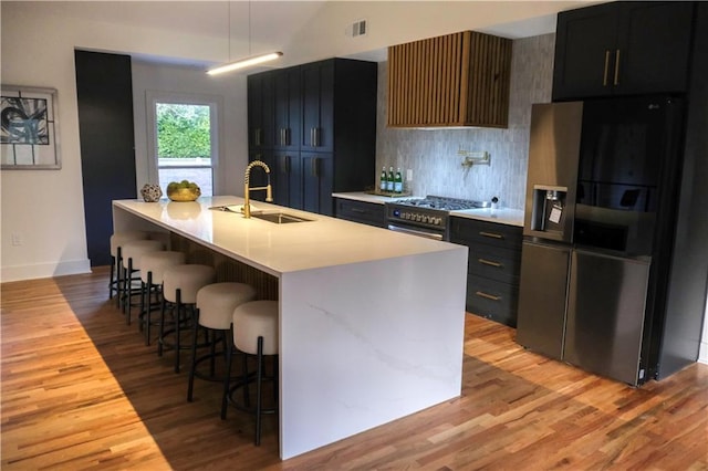 kitchen featuring a breakfast bar, a sink, black fridge with ice dispenser, light countertops, and dark cabinetry