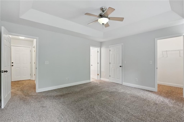 199 Rocky Shoals Trl, Mount Airy, GA 30563 - unfurnished bedroom with a tray ceiling, carpet floors, baseboards, a walk in closet, and ceiling fan