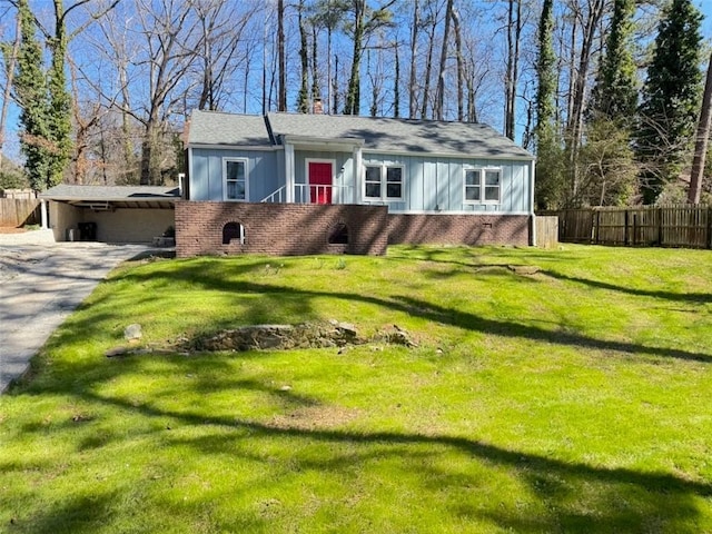 view of front of home with brick siding, fence, concrete driveway, a chimney, and a front yard