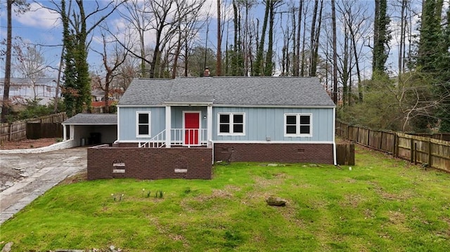 view of front facade with board and batten siding, roof with shingles, fence, and a front lawn