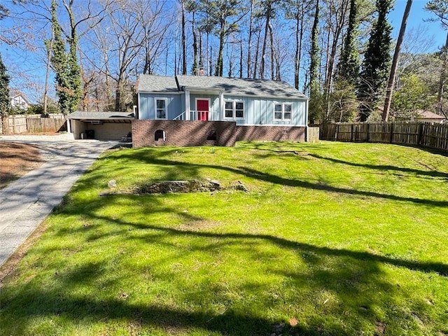 view of front facade featuring driveway, brick siding, fence, and a front yard