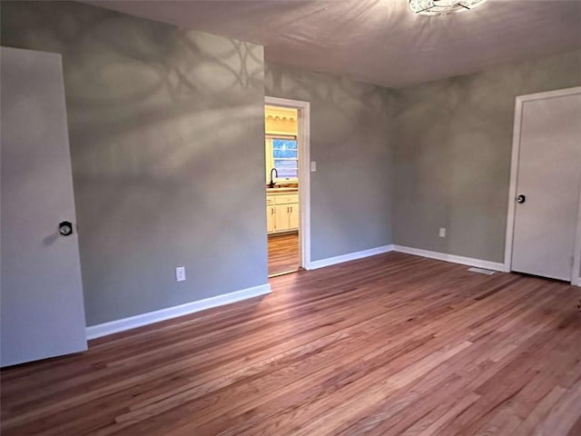 empty room with hardwood / wood-style floors and sink