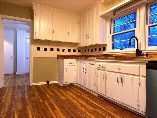 kitchen with decorative backsplash, dark wood-type flooring, sink, black dishwasher, and white cabinetry