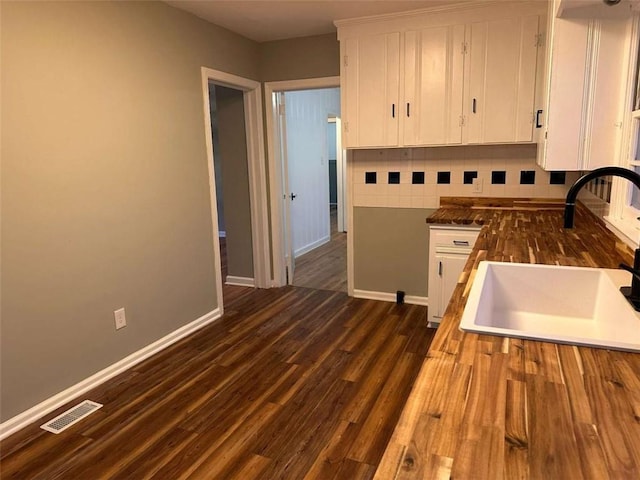 kitchen with backsplash, white cabinetry, sink, and dark wood-type flooring