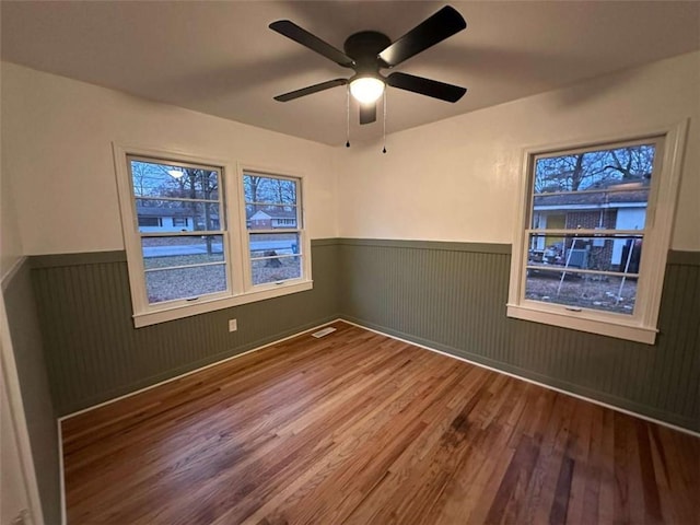 spare room featuring hardwood / wood-style flooring, ceiling fan, and wood walls