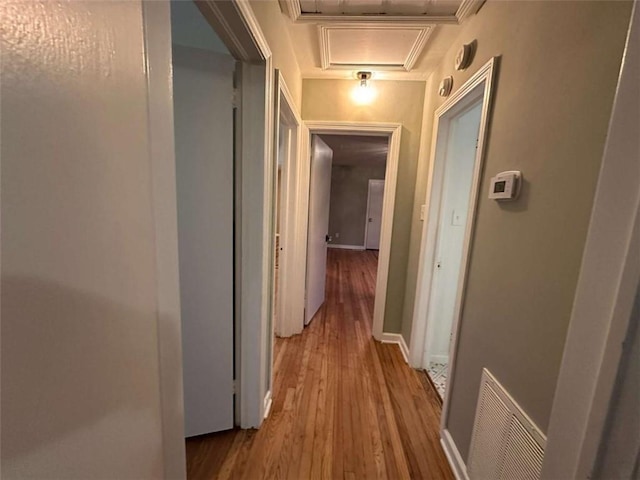 corridor with light hardwood / wood-style floors and ornamental molding