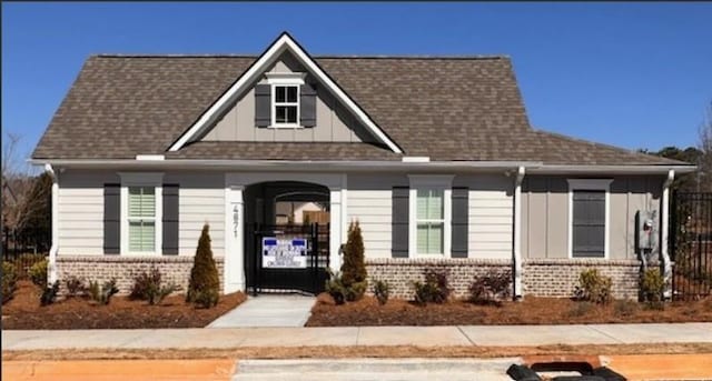 view of front facade featuring board and batten siding, brick siding, and a shingled roof