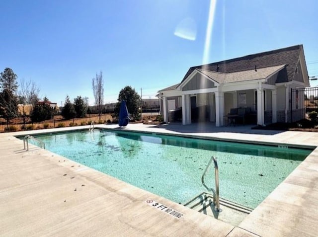 community pool with a patio and fence