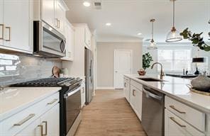 kitchen with light countertops, decorative backsplash, appliances with stainless steel finishes, white cabinetry, and a sink