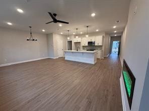 kitchen with stainless steel microwave, white cabinets, dark wood-type flooring, and open floor plan