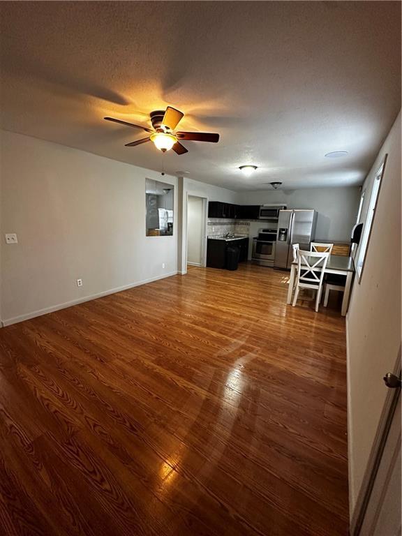 5022 Cliff Top Dr, Loganville, GA 30052 - unfurnished living room featuring baseboards, a ceiling fan, and dark wood-type flooring