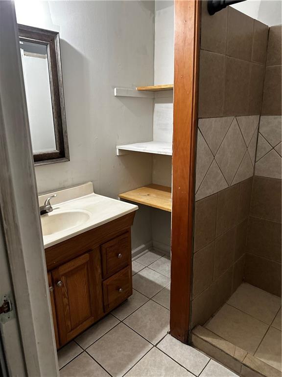 5022 Cliff Top Dr, Loganville, GA 30052 - bathroom featuring vanity, tile patterned flooring, and a tile shower