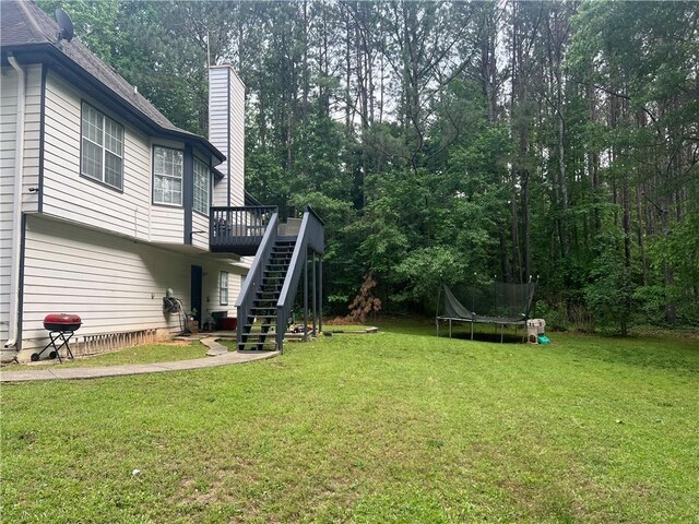 5022 Cliff Top Dr, Loganville, GA 30052 - rear view of property featuring a garage, a trampoline, a chimney, a wooden deck, and stairway