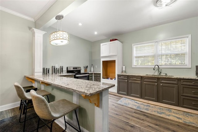 kitchen featuring kitchen peninsula, white cabinets, hanging light fixtures, electric range, and sink