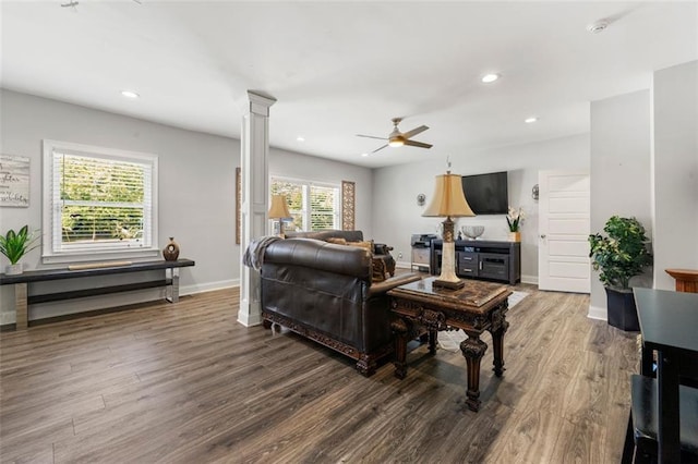 living room with dark wood-type flooring, ceiling fan, and decorative columns