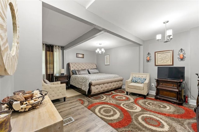 bedroom featuring light hardwood / wood-style floors, beam ceiling, and an inviting chandelier