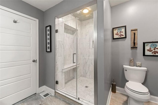 bathroom featuring toilet and a shower with shower door