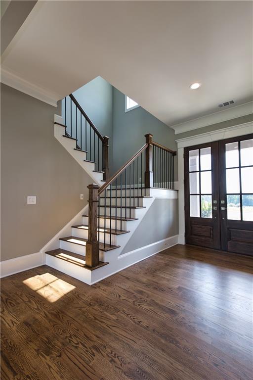 interior space with hardwood / wood-style floors, ornamental molding, and french doors