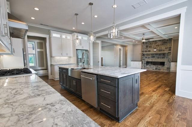 kitchen featuring stainless steel dishwasher, coffered ceiling, white cabinets, beam ceiling, and a fireplace