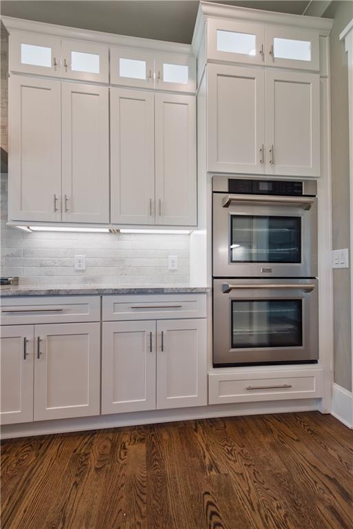 kitchen with dark hardwood / wood-style flooring, decorative backsplash, white cabinetry, and double oven