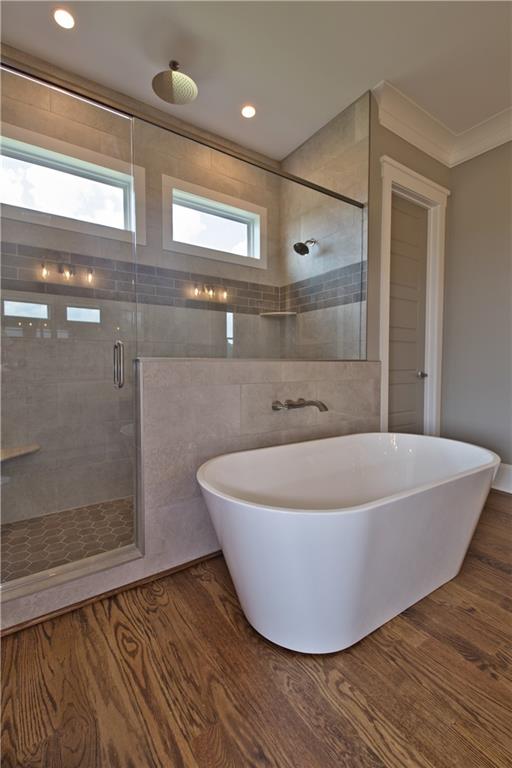 bathroom featuring wood-type flooring, ornamental molding, and a shower with door